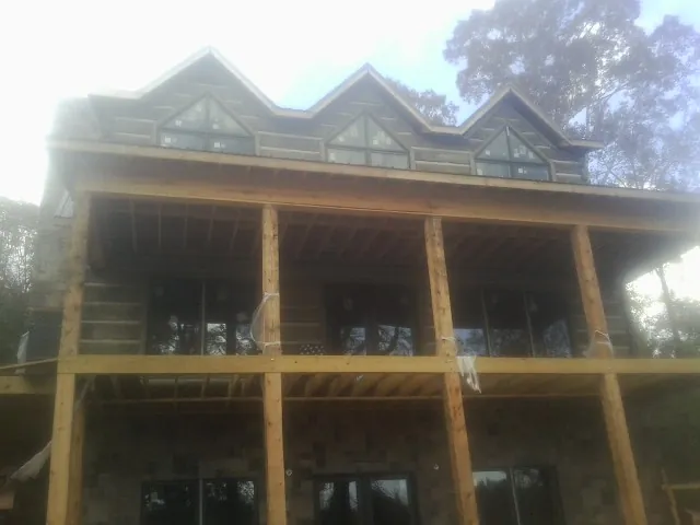 Dormers and porch framing on a large log home under construction — Roof Coating work by our crew in Wahpeton