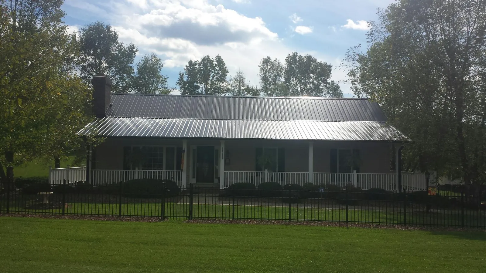 Gray metal roof on a brick ranch with a full width front porch — Gutter Guard Installation work by our crew in Wahpeton