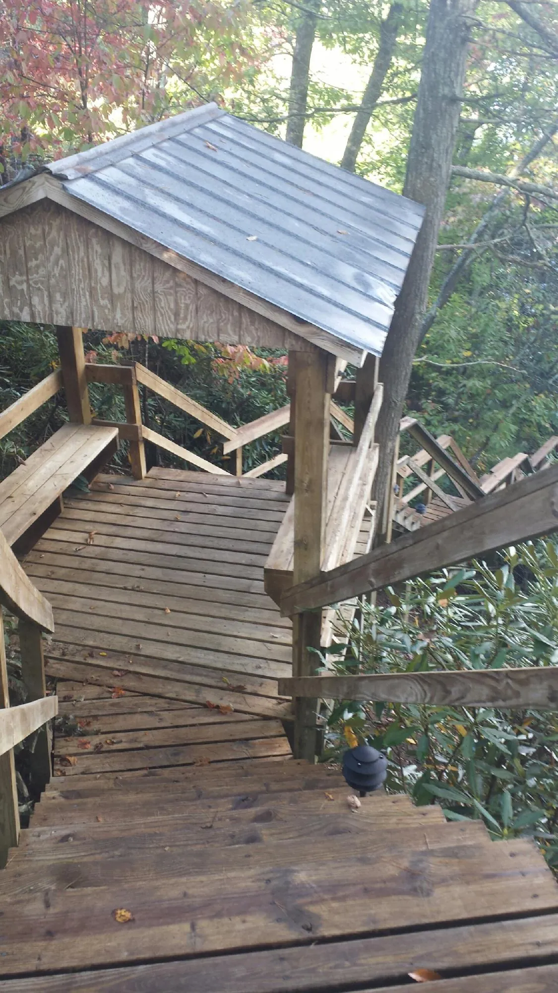 Metal roofed shelter over wooden steps on a wooded walkway — Skylight Repair & Installation work by our crew in Wahpeton