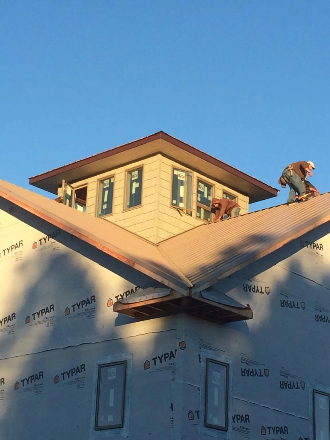 Roofers working around a rooftop cupola on a new metal roof at sunset — Roof Waterproofing in Wahpeton by Roofing Brothers